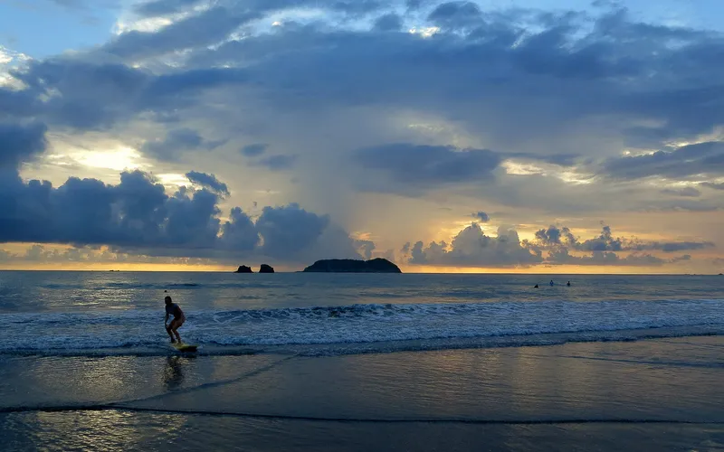A surfer glides in at dusk
